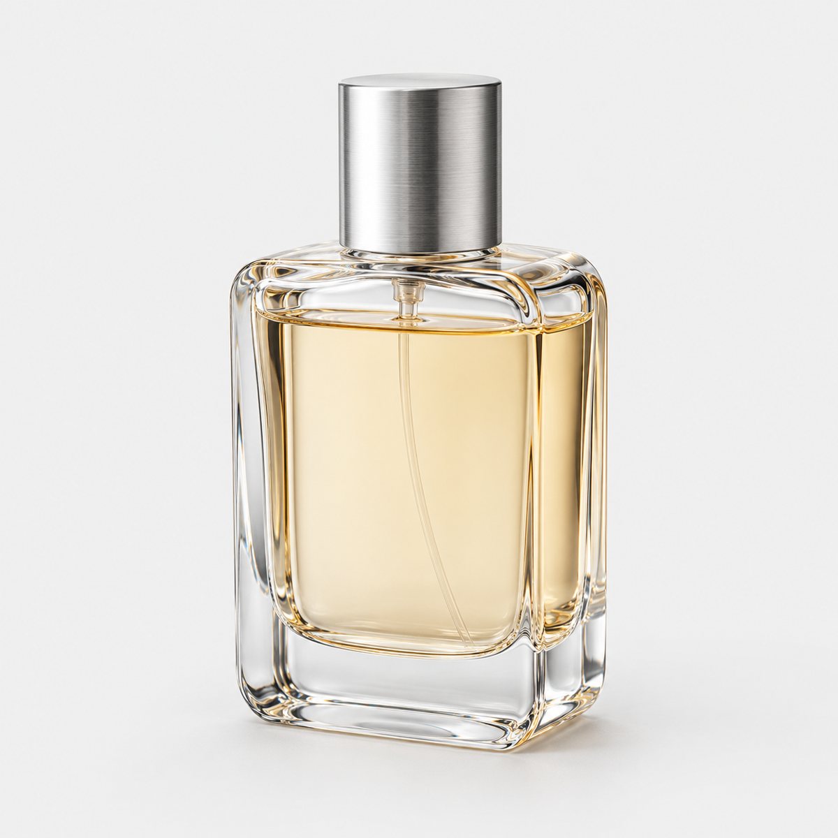 The original photo: a clear rectangular glass perfume bottle with pale champagne liquid and a brushed silver cap, on a plain light grey background